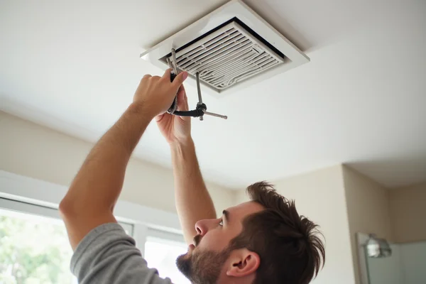 New bathroom exhaust fan installation with electrician connecting wiring in ceiling