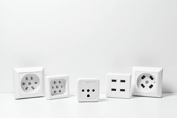 Various types of modern power points including USB power points and smart power points arranged on a white surface