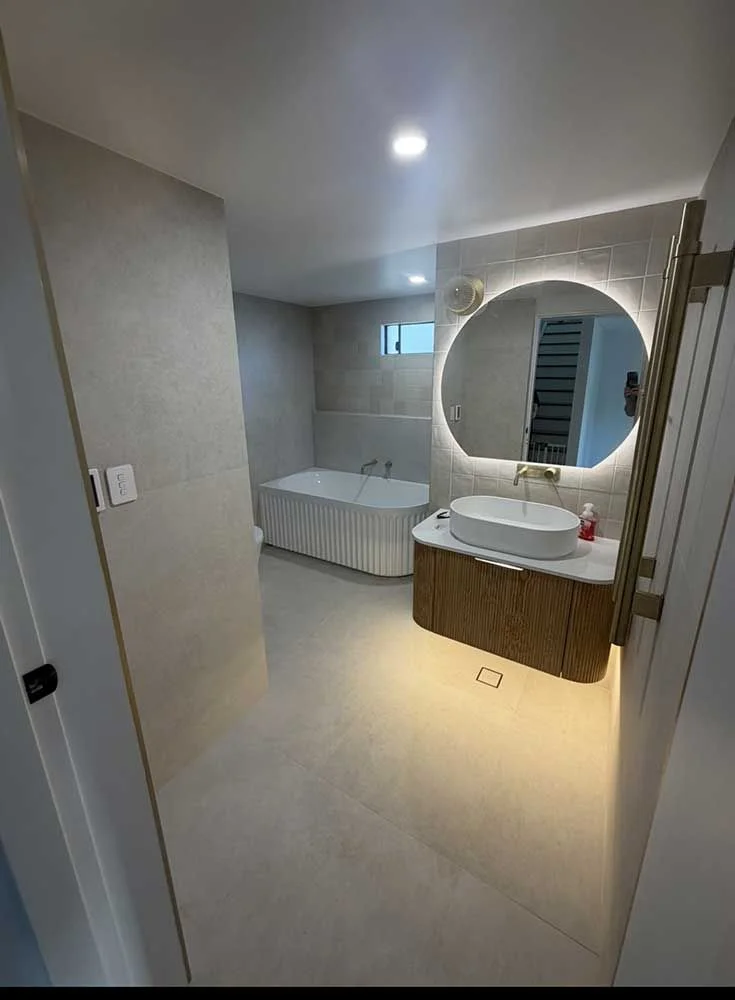 Luxury bathroom renovation by MTS Group — fluted freestanding bath, LED backlit mirror and timber vanity with under-cabinet lighting