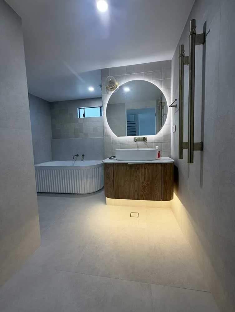 Modern bathroom renovation featuring freestanding bath, round LED mirror and floating timber vanity by MTS Group