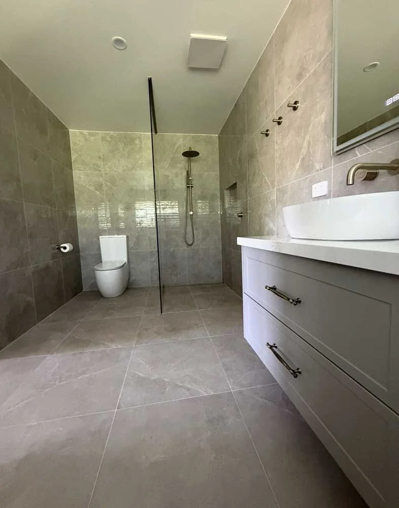 Modern walk-in shower renovation with marble-look tiles, frameless glass screen and shaker-style vanity by MTS Group