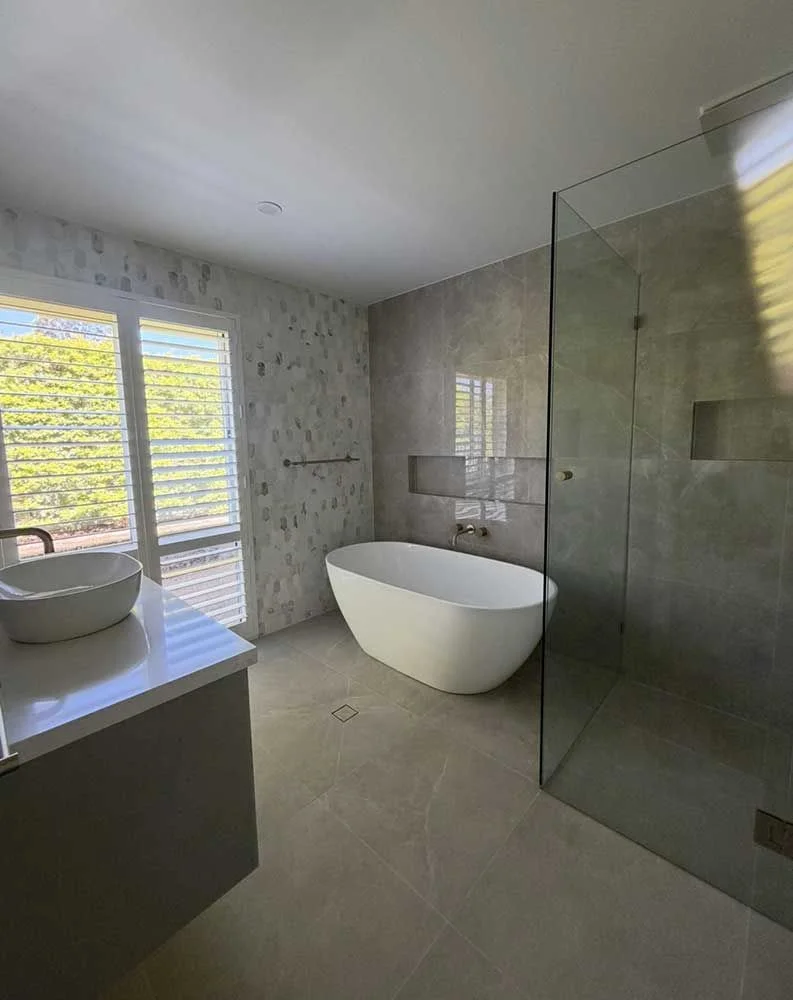 Elegant bathroom renovation with freestanding bath, feature wall tiling and frameless glass shower by MTS Group