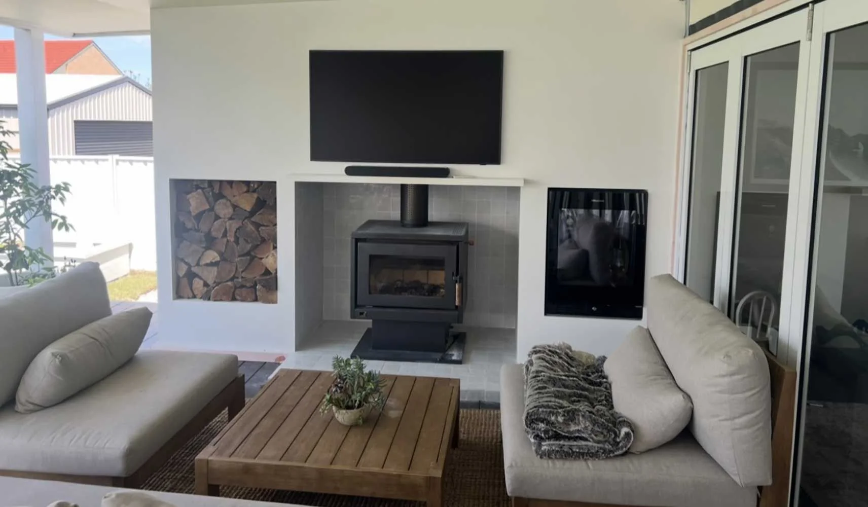 Completed outdoor entertaining area with built-in wood heater, firewood storage, TV mount and custom joinery by MTS Group