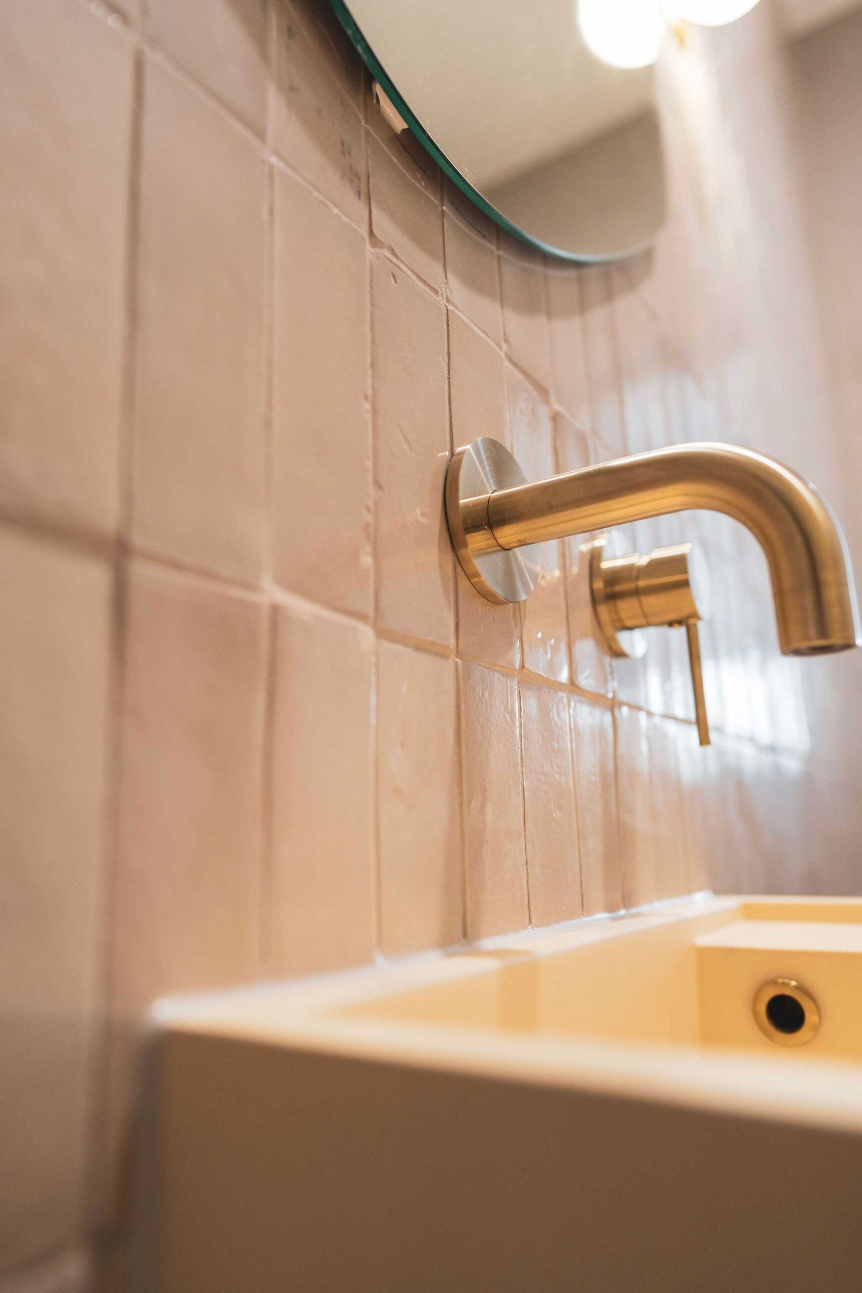 Bathroom detail — brushed brass wall-mounted tap and handmade blush tiles by MTS Group