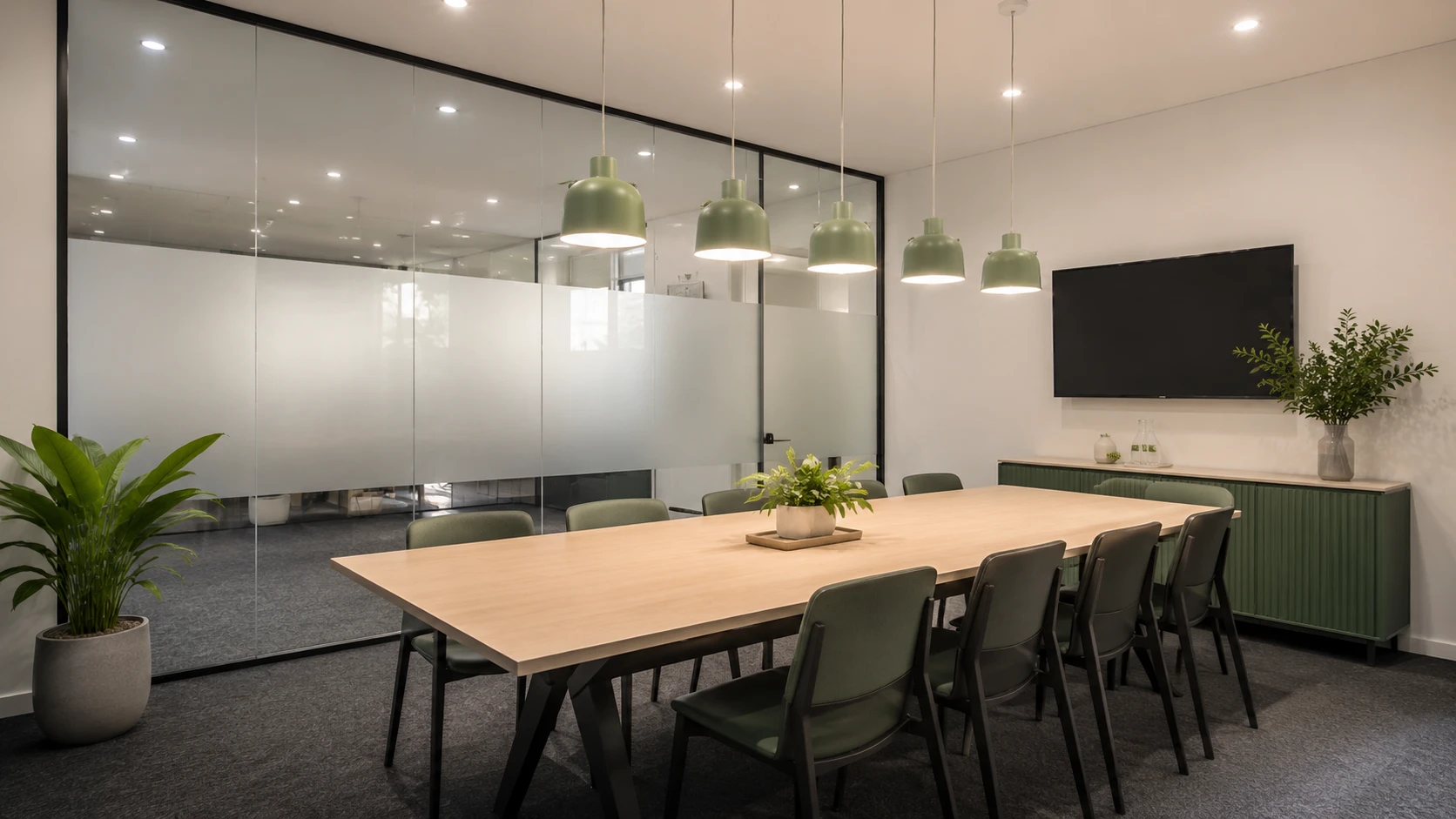 Boardroom fitout with a timber meeting table, pendant lighting and wall-mounted display