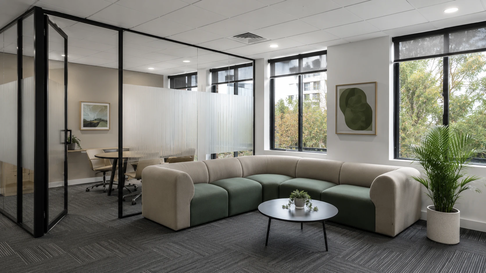 Commercial breakout seating area with modular lounge seating beside a glazed meeting room