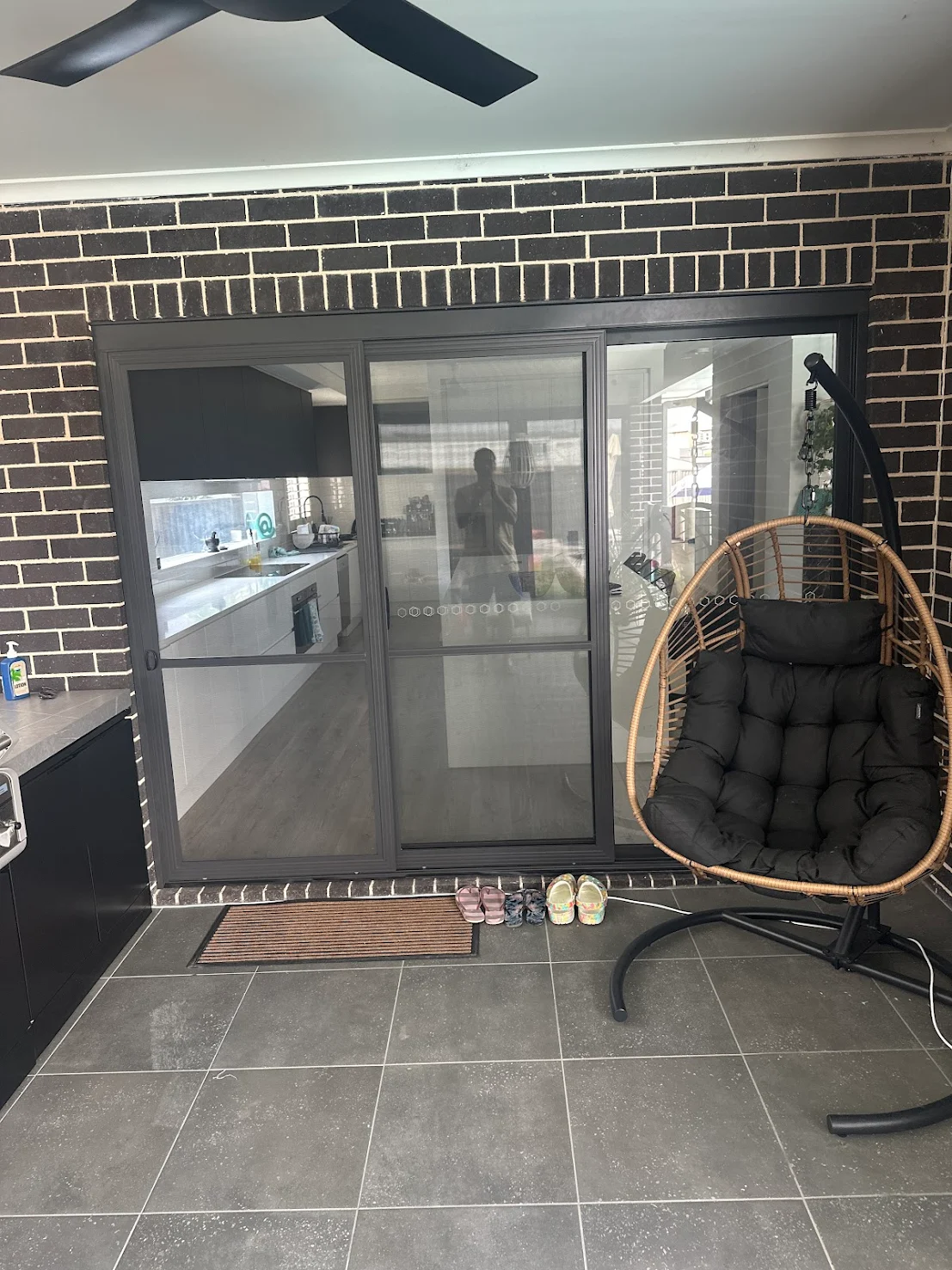 Outdoor alfresco area renovation with tiled flooring, sliding doors and dark brick feature wall by MTS Group